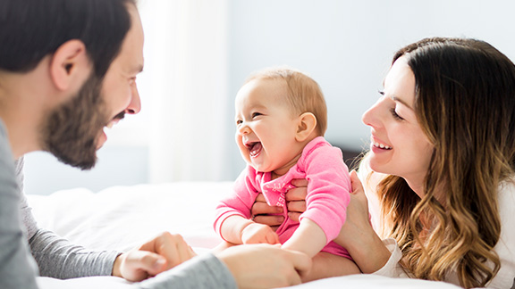 A cute baby fun with parents on the bed